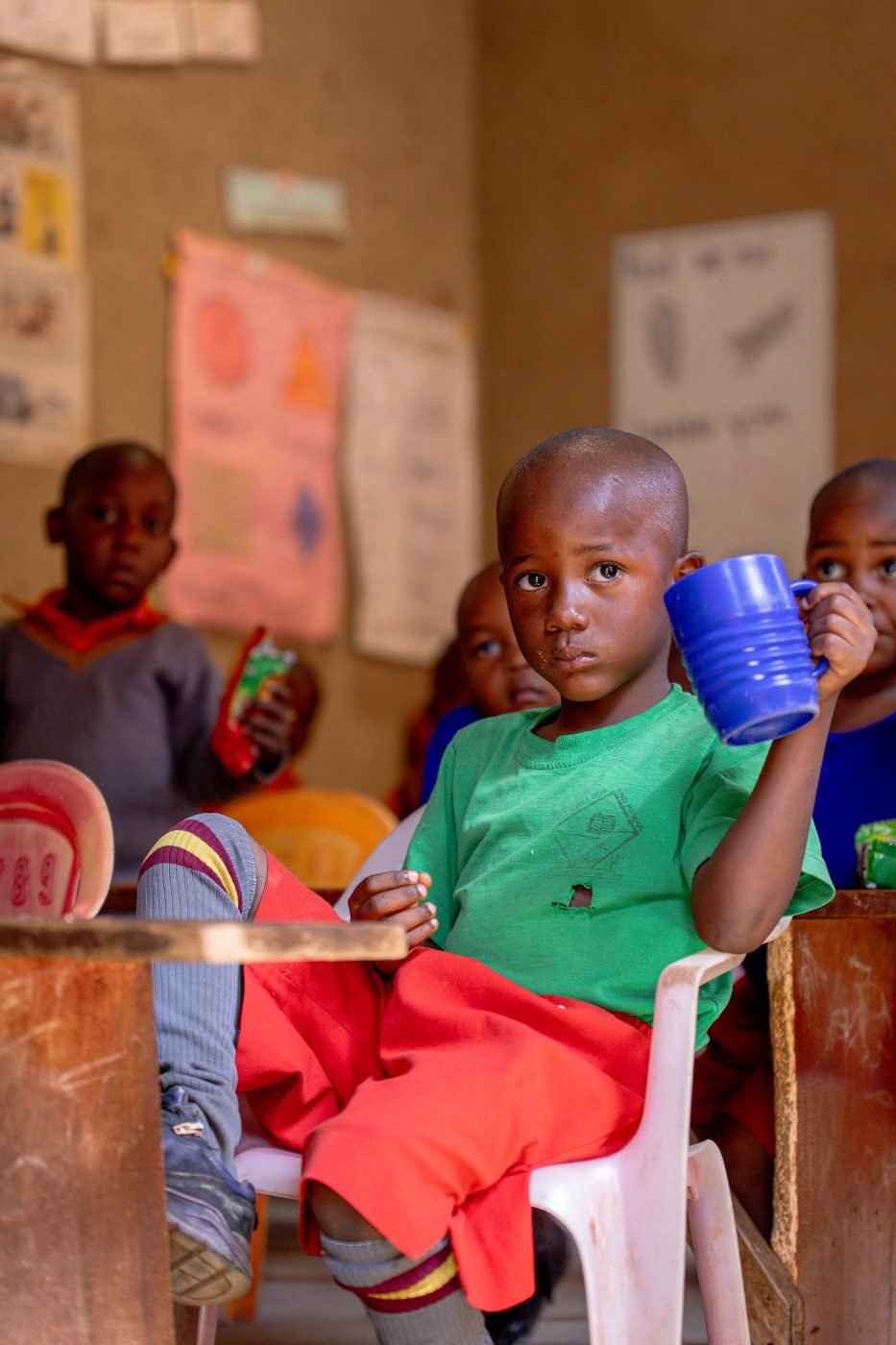 A pupil drinking from a cup in a classroom