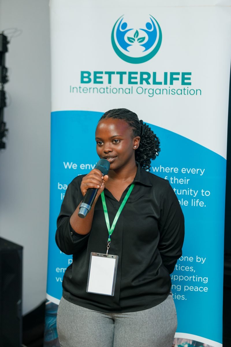 Speaking beside the BetterLife banner at LCOY Uganda 2026