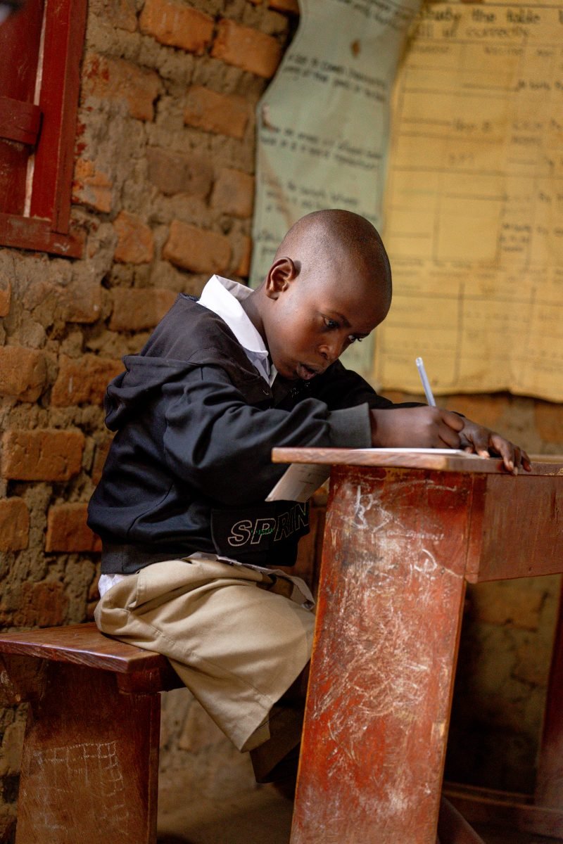 A pupil writing at his desk in Rukungiri