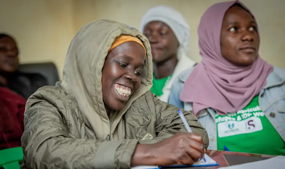 A woman laughing as she writes during a training session