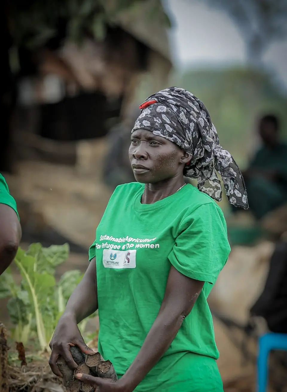 A woman in a programme T-shirt holding seedlings ready to plant in Yumbe