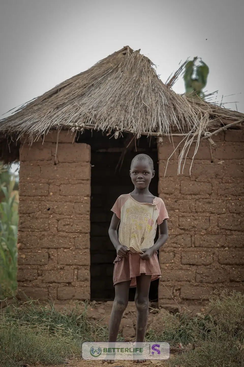 A girl standing outside a thatched home